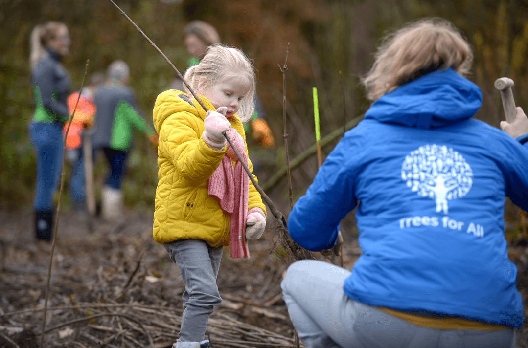 Een kind loopt met een boom die geplant moet worden.