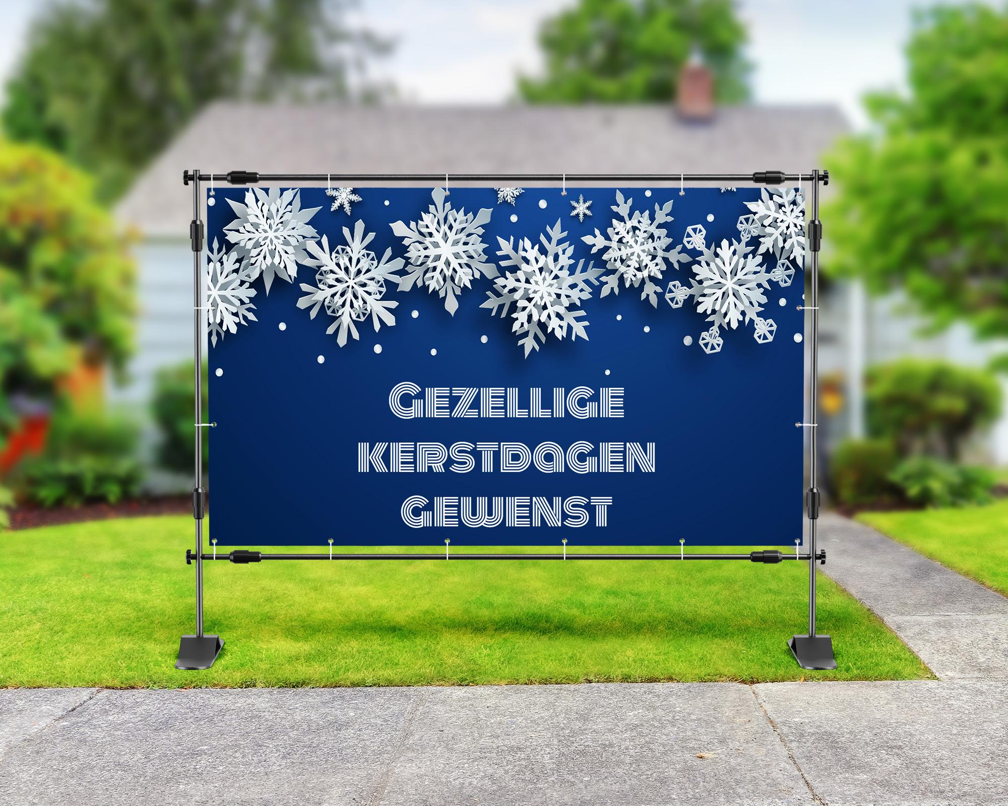 Spandoek kerst met blauwe achtergrond, witte sneeuwvlokken en de tekst ‘Gezellige kerstdagen gewenst’, geplaatst in een tuinomgeving.
