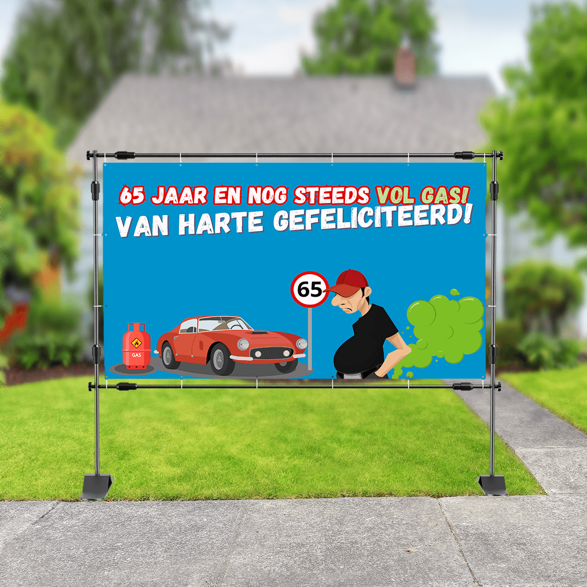 Spandoek in tuin met tekening van een auto, gasfles en man die een scheet laat, met de tekst: '65 jaar en nog steeds vol gas! Van harte gefeliciteerd'